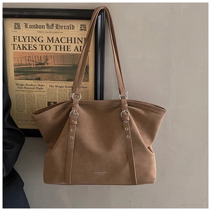 Detail view of brown matte leather tote bag with silver hardware and fashion logo