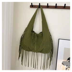 Detailed close-up of grass green suede tote bag with long bohemian fringes and tie closure