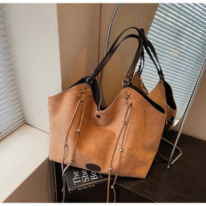 Gros plan du sac cabas en daim caramel avec poignées en cuir et détails de billes en métal