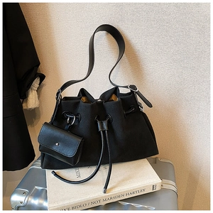 Detail of black drawstring bucket bag with yellow lining on a silver suitcase