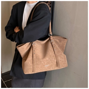 Close-up of brown suede tote bag with silver eyelets and fashion leather text details