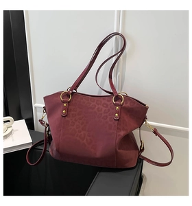 Close-up of burgundy leopard print tote bag with gold hardware and dual straps