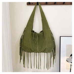 Detailed close-up of dark green suede tote with long tassels and woven texture