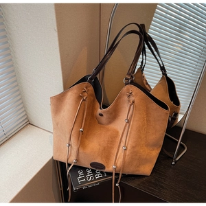 Détail du sac cabas en daim marron avec cordons à perles argentées et base en cuir fin