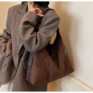 Detail of dark brown suede hobo bag with metal eyelets and side zipper pocket
