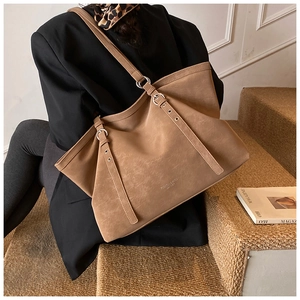 Macro shot of brown leather tote bag showing fine texture and silver metal buckle details