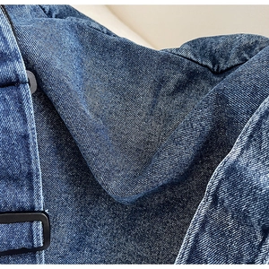 Dettaglio della borsa in denim blu vintage con texture lavata e fibbia in metallo nero