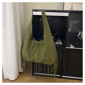 Detail of green faux suede tote bag featuring bohemian tassels and drawstring accents