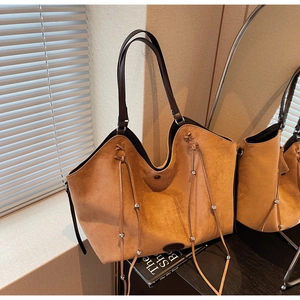 Gros plan sur un sac cabas en daim caramel avec des cordons à glands et perles
