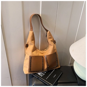 Detail der gelben Wildledertasche mit braunen Ledertaschen und Metallnieten-Akzenten