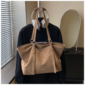 Detail of brown faux leather tote bag with adjustable straps and fashion typography