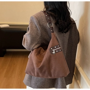 Detail of vintage brown suede shoulder bag showing metal rings and zipper pockets