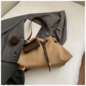 Detail of suede tote bag with drawstring closure and detachable coin purse on grey suit