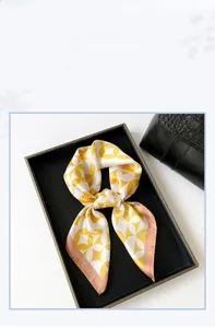 Detail of silk satin square scarf with yellow floral patterns on a luxury handbag