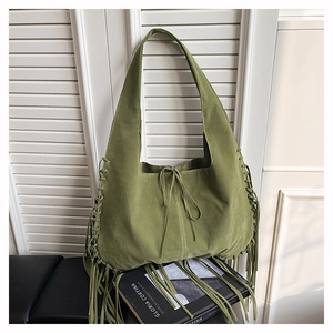 Detail view of olive green suede tote bag with woven fringe accents and drawstring closure