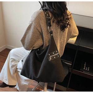 Detail of black suede Hobo bag featuring silver rivet straps and side zipper accents