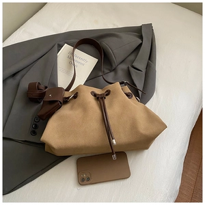 Macro view of khaki suede drawstring bucket bag with leather strap and mini pouch