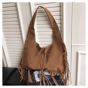 Close-up of brown suede hobo bag with bohemian long fringe and woven lace detail