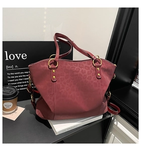 Detail of dark red tote bag with leopard print texture and gold ring hardware accents