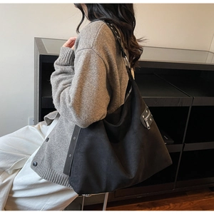Detail view of black velvet tote bag featuring silver metal zippers and wide shoulder strap