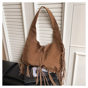 Detailed view of bohemian caramel suede tote bag featuring long fringes and drawstring closure