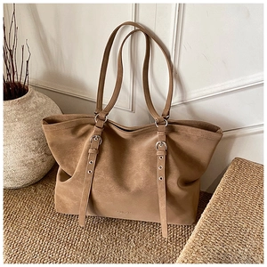 Detail of khaki suede tote bag showing metallic eyelets and adjustable shoulder straps