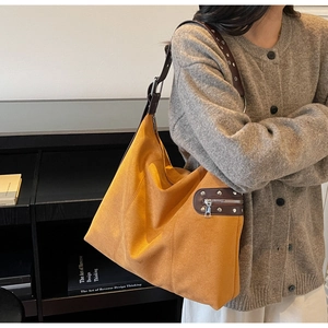 Detail of ginger suede tote bag featuring dark brown leather strap with silver eyelets