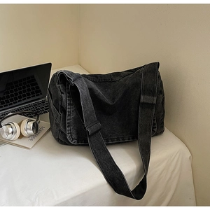 Dettaglio della borsa a tracolla in denim nero lavato con ampia tracolla regolabile