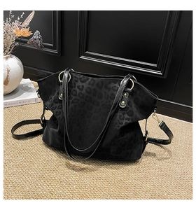 Detail of black leopard jacquard tote bag with golden hardware and adjustable strap