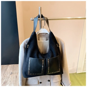 Detail der schwarzen Wildleder-Einkaufstasche mit Metallnieten und symmetrischen Taschen