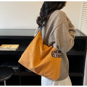 Close-up of mustard yellow faux suede tote bag with brown straps and silver metal rivets