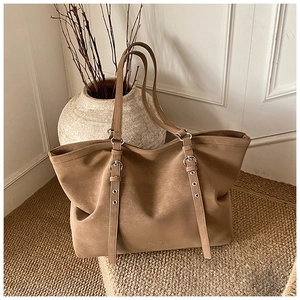 Detailed close-up of khaki matte tote bag featuring vertical metal buckle straps and slim handles