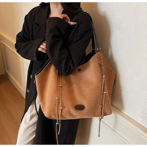 Détail d'un grand sac cabas en daim marron avec cordon à franges et bandoulière