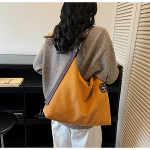 Detail of oversized amber suede tote bag with leather strap and eyelet studs
