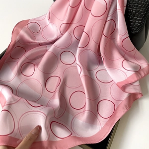 French style polka dot silk scarf in pink tied to a black crocodile texture handbag