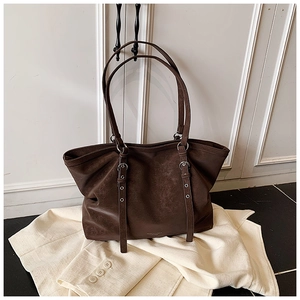 Macro view of dark brown vintage leather tote bag showing clear texture and silver buckles