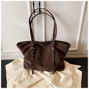 Detail of dark brown tote bag featuring retro matte leather and silver metal buckles