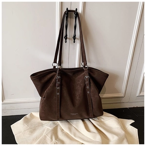 Close-up of vintage dark brown tote bag showing leather texture and metal buckle detail