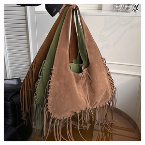 Macro detail of bohemian suede tote bag featuring fringe tassels and visible stitching