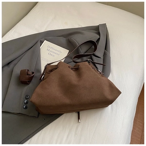 Macro shot of dark brown suede shoulder bag showing metal eyelets and drawstring detail