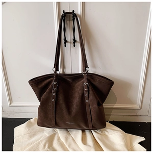 Detail of dark brown leather tote bag showing silver metal buckles and logo print