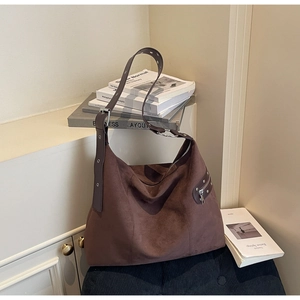 Macro detail of dark brown suede tote bag featuring metallic grommets and vintage zippers