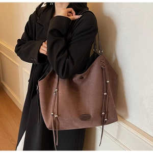 Détail d'un grand sac cabas en daim marron avec des franges et des perles métalliques