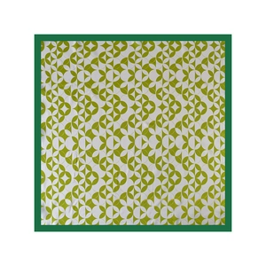 Detail of square silk scarf showing geometric green patterns and high-quality fabric texture