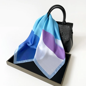 Detail of color-block silk scarf draped on a luxury black croc-embossed handbag