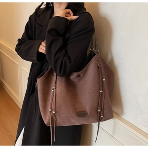 Détail du grand sac cabas en daim marron avec perles argentées et lanières en cuir