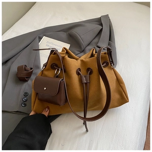Detail of mustard yellow bucket bag with brown leather straps on white bedding