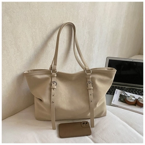 Detail of spacious beige tote bag with decorative metal ring straps and phone for scale