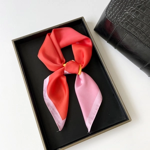 Detailed macro view of the satin texture and neat stitching on this pink silk square scarf