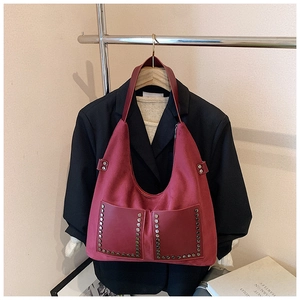 Nahaufnahme der Vintage-Tote-Bag aus weinrotem Wildleder mit Nieten und Fronttaschen